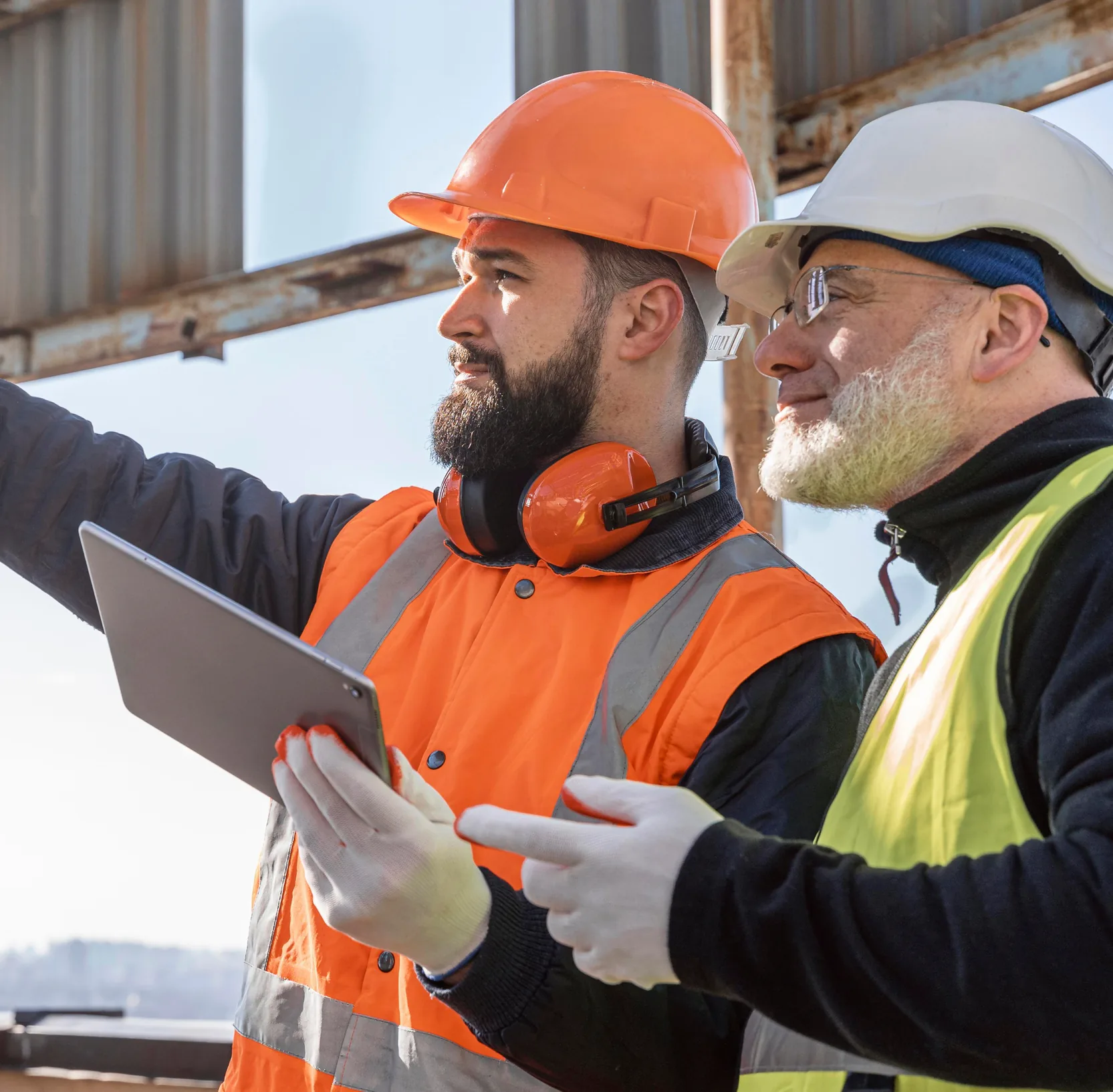 Twee havenmedewerkers met helm en veiligheidsvest overleggen bij een tablet